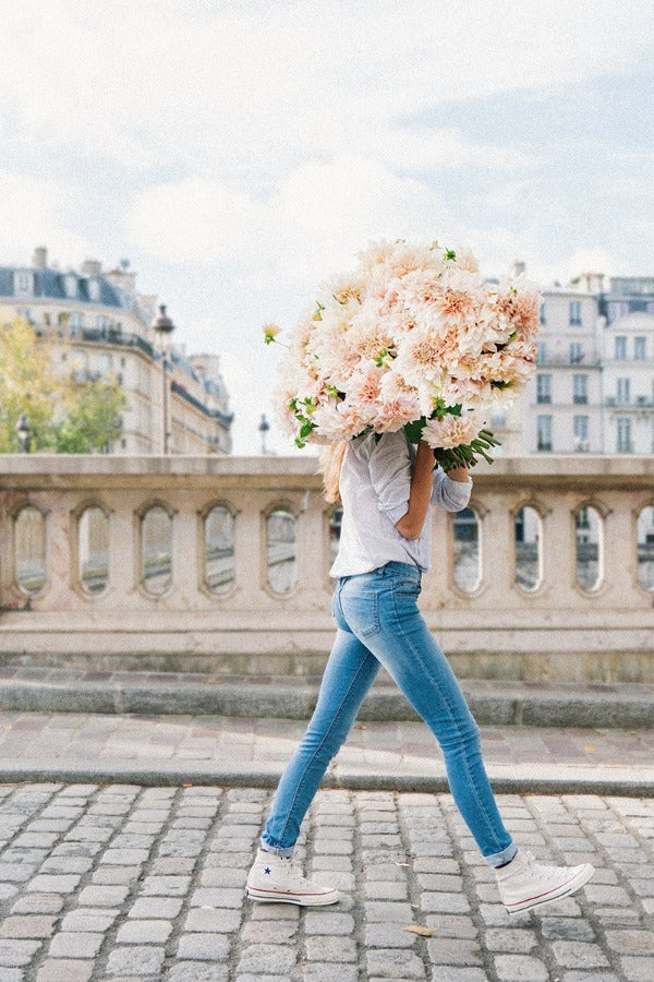 Joyful & Unstoppable is a photo of a girl in Paris in Ile St Louis with the biggest bunch of pink dahlias and is part of a limited edition series named Young Girl in Bloom by photographer Carla Coulson celebrating women loving and believing in themselves and building their self esteem by trusting their intuition.