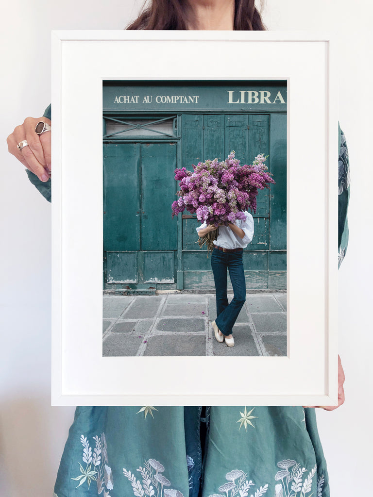 Beauty In Balance is a photo of a girl in St Germain des Prés holding a big bunch of lilacs and is part of a limited edition series named Young Girl in Bloom by photographer Carla Coulson celebrating women loving and believing in themselves and building their self esteem by trusting their intuition.