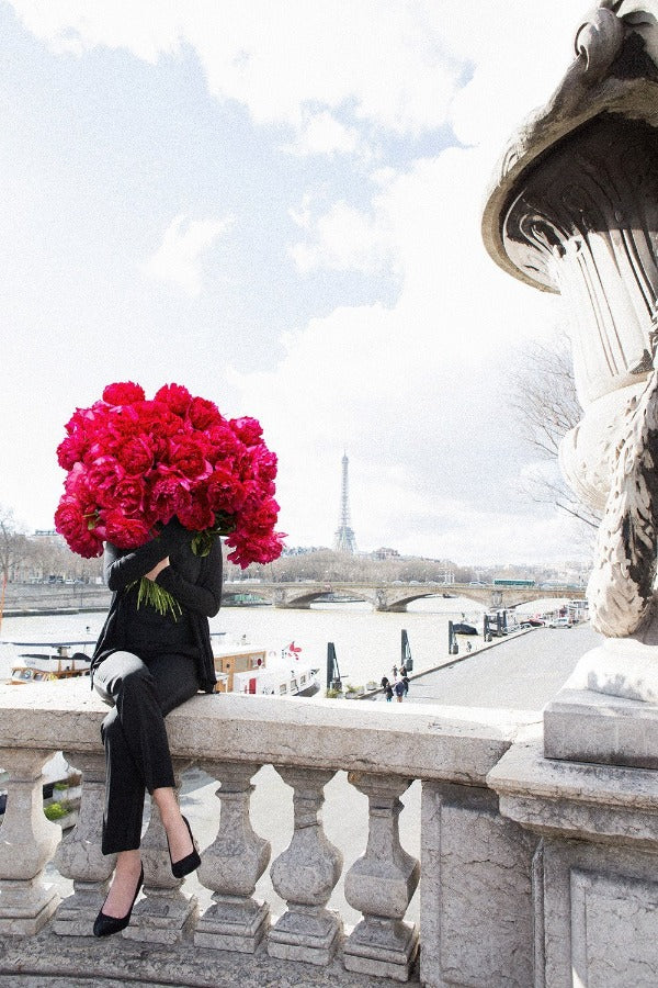 Bold Beauty is a photo of a girl on the Pont Alexandre III in Paris with a beautiful bouquet of red peonies and is part of a limited edition series named Young Girl in Bloom by photographer Carla Coulson celebrating women loving and believing in themselves and building their self esteem by trusting their intuition.
