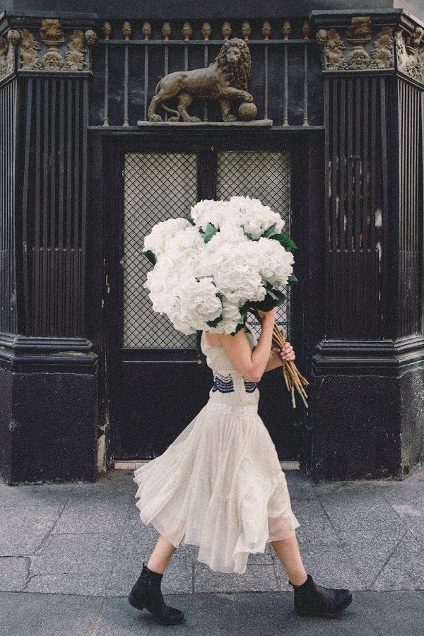 Going Places is a photo of a girl in the 10th Arrondissement in Paris with a big beautiful bunch of white hydrangeas and is part of a limited edition series named Young Girl in Bloom by photographer Carla Coulson celebrating women loving and believing in themselves and building their self esteem by trusting their intuition.
