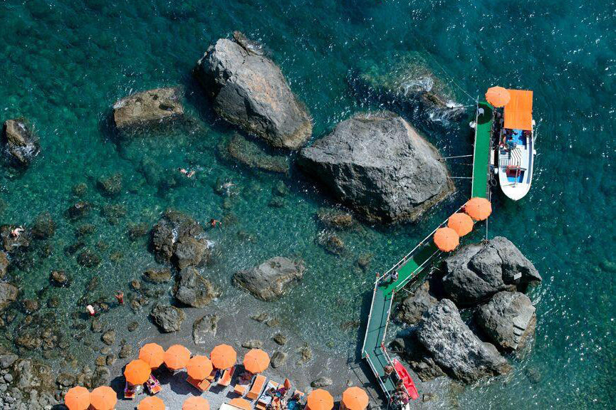 Santa Croce beach on the Amalfi coast with orange umbrellas and a wooden boat